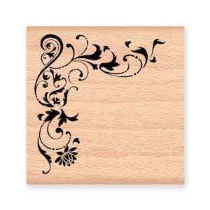 May include: A wooden stamp with a black floral design in the corner. The design features intricate swirls and leaves.