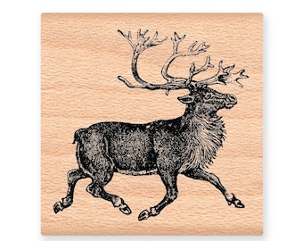 May include: A black and white illustration of a reindeer with large antlers running to the right. The image is printed on a light brown wooden block.