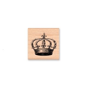 May include: A wooden stamp with a black and white illustration of a crown with ornate details.
