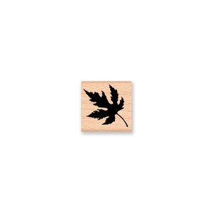 May include: A black silhouette of a maple leaf on a wooden block.