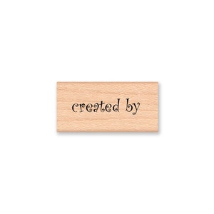 May include: Wooden stamp with the text "created by" in a decorative font.