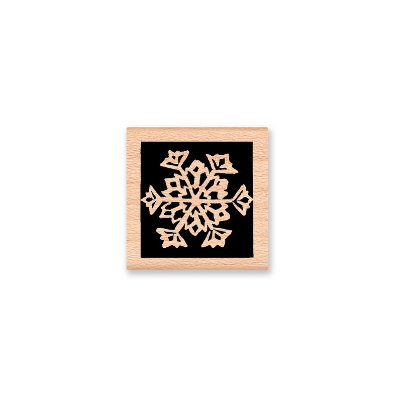 Puede incluir: Un sello de madera con fondo negro y un dise&ntilde;o de copo de nieve blanco.