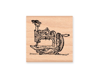May include: A vintage-style sewing machine illustration on a wooden block stamp. The machine has a decorative design with a hand crank and a needle.