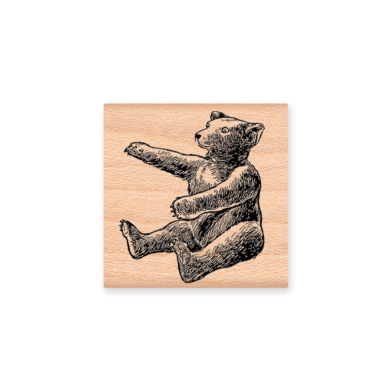 May include: A black and white line drawing of a bear sitting on its haunches with its paws outstretched. The bear is facing to the right and has a simple, cartoon-like style.