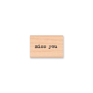 May include: Wooden rubber stamp with the text "miss you" in black ink.