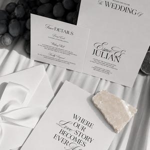 Puede incluir: Un conjunto de papelería de boda con tarjetas blancas y tipografía negra en estilo serif y cursiva. La invitación principal dice The Wedding of Esme & Julian, acompañada de una tarjeta Finer Details y una tarjeta que dice Where Our Love Story Becomes Ever After.