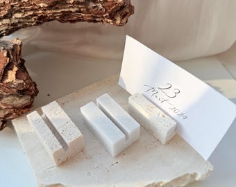 May include: A selection of small, rectangular stone card holders in different textures and colours. A white card with the date "23 Mart 2024" is propped up in one of the holders. The holders are on a textured stone slab.