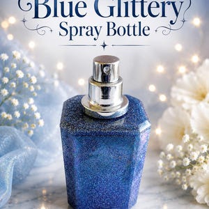 May include: A blue glittery spray bottle with a faceted, multi-sided glass body and a metallic silver pump nozzle. The text "Blue Glittery Spray Bottle" is printed in dark blue script at the top of the image above the container.