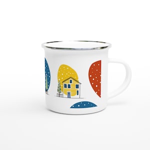 Könnte beinhalten: Ein weißer Emaillebecher mit einem farbenfrohen Grafikdruck eines gelben Hauses mit blauer Tür, einem kleinen Zaun und einem Baum. Das Design zeigt abstrakte blaue, gelbe und rote Formen mit weißen Punkten, die Schnee auf weißem Grund darstellen.