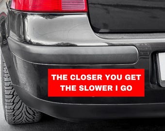 May include: A black car with a red bumper sticker that reads "The closer you get the slower I go."