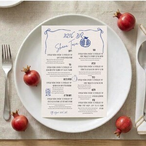 May include: A rectangular paper card featuring blue text and illustrations for Rosh Hashanah, including the Hebrew phrase Shana Tova, a pomegranate, and various blessings in both Hebrew and English, centered on a white plate with pomegranates.