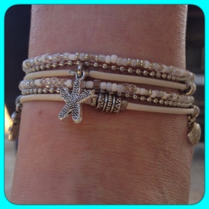 Puede incluir: Una pulsera de varias hebras con cordones de cuero blanco, cadenas de bolas plateadas y cuentas de vidrio transparente. Incluye un dije central de estrella de mar plateada con superficie texturizada y dijes pequeños en forma de concha.