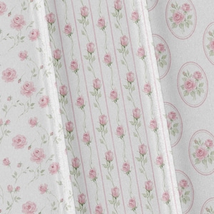 May include: Close-up of three fabric swatches with floral patterns. One features scattered pink roses on a white background. Another has vertical pink stripes with rose vines. The third has pink rose bouquets in oval frames.