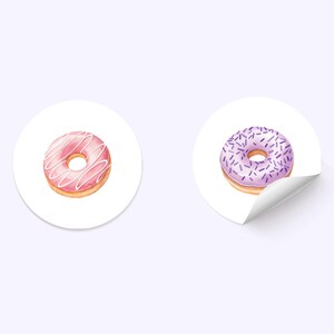 Puede incluir: Dos pegatinas redondas con im&aacute;genes de donuts. Una dona es rosa con glaseado blanco y la otra es morada con chispas moradas.