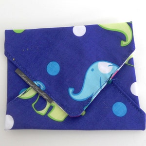 May include: A folded, fabric envelope-style wallet. The wallet is navy blue with a pattern of white and blue polka dots and light blue elephants. The interior is a contrasting pink fabric. A small tag reads "Totes and Handlings."