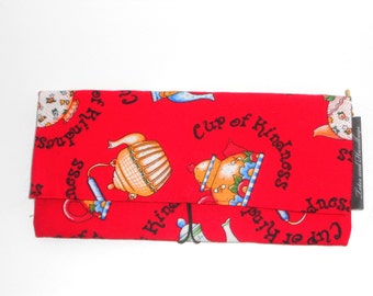 May include: A red fabric wallet with a repeating pattern of teapots and the words "Cup of Kindness." The wallet has a fold-over flap and a black elastic closure. The label "Lotes and Handbags" is visible.