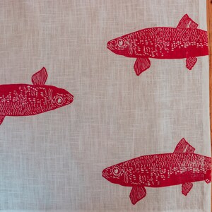 May include: A white linen tea towel with a red fish design. The fish are printed in a simple, blocky style.