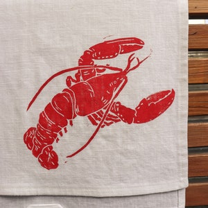 May include: A red lobster print on a white linen tea towel.