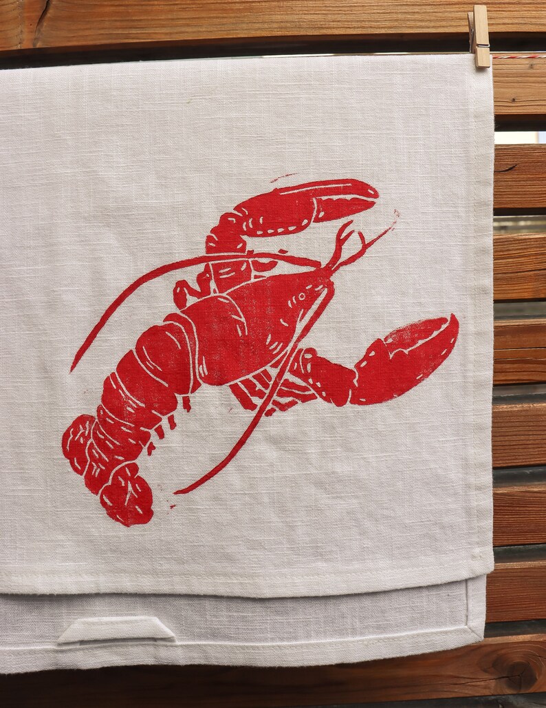 May include: A red lobster print on a white linen tea towel.