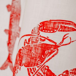 May include: Red lobster and fish printed on a white linen tea towel.