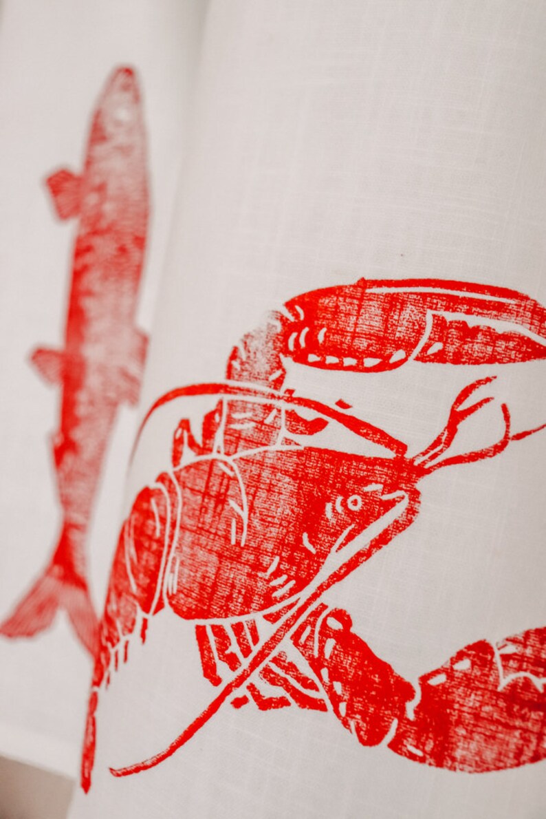 May include: Red lobster and fish printed on a white linen tea towel.