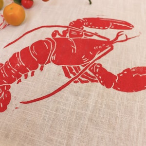 May include: Red lobster print on a white linen tea towel.