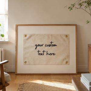 Individuell besticktes Banner mit Textzitat, handgestickte Typografie-Wandkunst, neutrale Wohndekoration, modern-minimalistisch, personalisiertes Stickgeschenk