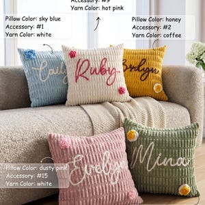 May include: Five square corduroy throw pillows in sky blue, cream, honey, dusty pink, and baby green. Each pillow features a custom embroidered name in cursive script and a small floral accessory. Text labels indicate pillow color, accessory number, and yarn color.