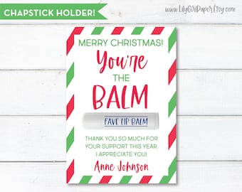 May include: A red and green striped card with the text "Merry Christmas! You're the Balm" and a white lip balm tube with the text "Fave Lip Balm". The card also includes the text "Thank you so much for your support this year. I appreciate you! Anne Johnson".