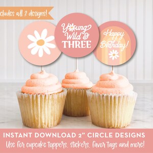 May include: Three cupcake toppers with pink and orange circles. The first topper has a white daisy with a yellow center. The second topper says "Young Wild & Three". The third topper says "Happy Birthday!" with a white daisy and orange stripes.