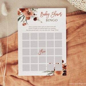 Może przedstawiać: Drukowana karta do gry w bingo na baby shower z kwiatowym wzorem w odcieniach pomarańczowego i brązowego. Karta ma siatkę 25 kwadrat&oacute;w z napisem "Free" w środkowym kwadracie. Tekst "Baby Shower Bingo" znajduje się na g&oacute;rze karty.