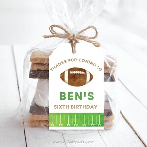 May include: White favour tag with green and brown football design. The tag says "Thanks for coming to Ben's Sixth Birthday!" with a green football pitch graphic at the bottom.