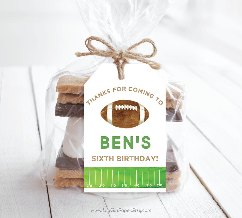 May include: White favour tag with green and brown football design. The tag says "Thanks for coming to Ben's Sixth Birthday!" with a green football pitch graphic at the bottom.