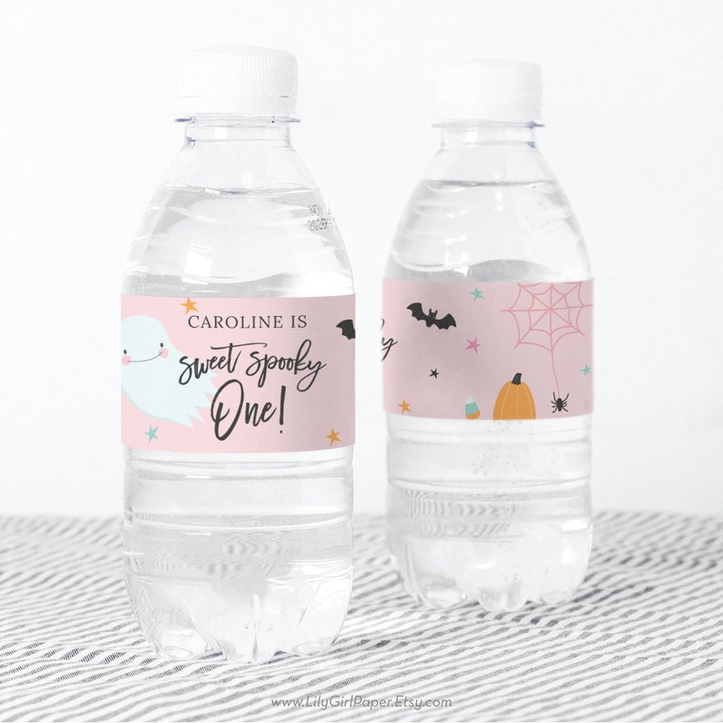 May include: Pink and white water bottle labels with a ghost, bats, a spider, a pumpkin, and candy corn. The text on the label reads "Caroline is sweet spooky one!"