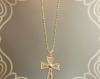 May include: A gold chain necklace with a delicate, filigree cross pendant. The cross is intricately designed with a floral pattern.
