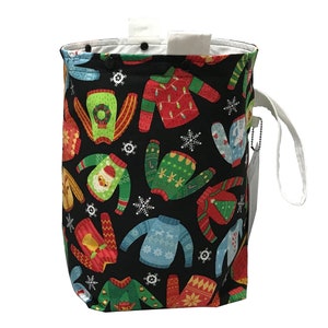 May include: A black canvas drawstring bag with a white handle. The bag is decorated with a pattern of colorful Christmas sweaters.