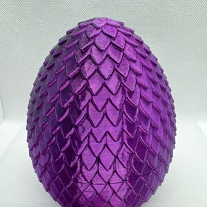 May include: A purple dragon egg with a textured, scaly surface. The egg is a decorative item and is made of a hard material.