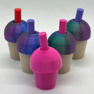 May include: Four colourful plastic cups with straws. The cups are iridescent blue, pink, and green. The straws are red, purple, and pink.