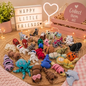 Può includere: Una collezione di piccole figure di animali articolate in plastica di vari colori e forme, tra cui un polpo, una tartaruga e varie creature, sparse su un tappetino rotondo intrecciato. Le figure presentano corpi segmentati e dettagli.