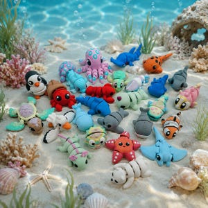 Puede incluir: Una colección de pequeñas figuras de animales articuladas hechas de plástico colorido, incluyendo un pulpo rosa, un cangrejo rojo, un tiburón azul, un pez payaso naranja y varias criaturas marinas, sobre arena con coral.