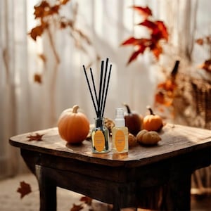 Könnte beinhalten: Ein rustikaler Holztisch zeigt eine herbstliche Anordnung. Ein kleiner Kürbis steht neben einem Glasdiffusor mit schwarzen Stäbchen. Eine Sprühflasche und mehrere Kürbisse sind ebenfalls vorhanden. Die Etiketten tragen die Aufschrift "Pumpkin Time".