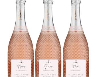 May include: Three bottles of Italian Rose sparkling wine with personalized labels. Each bottle has a white label with the text "Name" and "Your message here X" in black script font. The bottles are pink and have a textured diamond pattern.