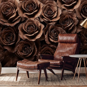May include: A brown leather armchair and ottoman sit in front of a wall covered in large, textured brown roses. A small side table with a white top and gold legs is next to the chair. A gold floor lamp and a woven basket complete the scene.
