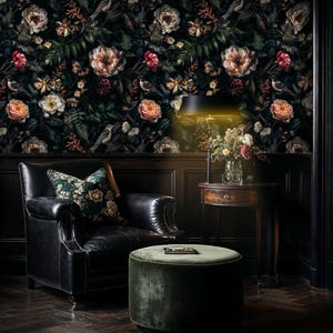 May include: A black leather armchair with a floral patterned cushion sits in front of a dark floral wallpaper. A green velvet ottoman sits in front of the chair. A table lamp with a black shade illuminates the scene.