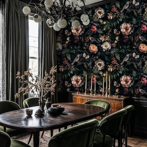 May include: A dark dining room with a floral wallpaper featuring pink and white roses, green leaves, and birds. The room has a dark wood table with six green velvet chairs, a chandelier, and a dark wood sideboard with candles.