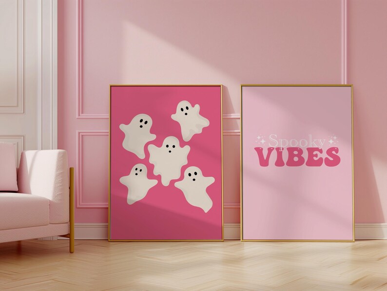 May include: Two pink framed prints with a Halloween theme. One print features five white ghosts on a pink background. The other print has the text "Spooky Vibes" in pink letters on a pink background.