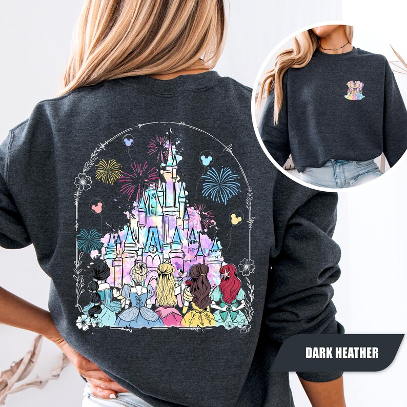 May include: Dark heather gray sweatshirt featuring a colorful castle graphic with fireworks and Disney princess silhouettes. The design includes floral and Mickey Mouse details. The sweatshirt has a crew neck and long sleeves. The text "DARK HEATHER" is at the bottom right.