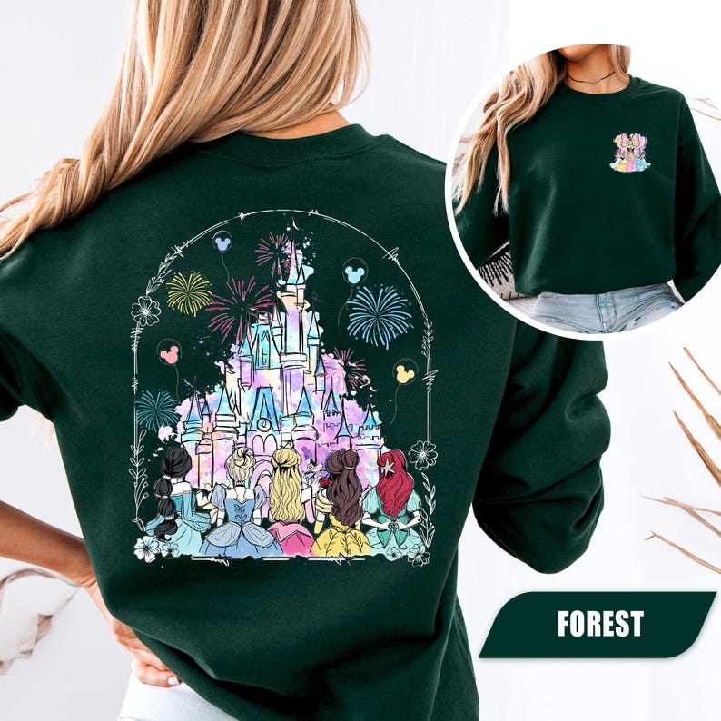 May include: A dark green sweatshirt featuring a colorful illustration of a castle with fireworks and several princess figures. The design is framed by a white arch with floral and balloon accents. The word "FOREST" is printed at the bottom.