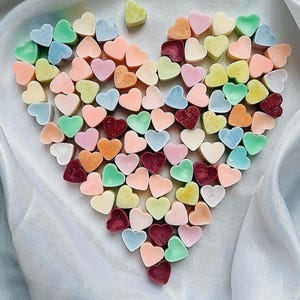 Peut inclure: Un arrangement en forme de cœur de petites fondantes de cire en forme de cœur colorées. Les fondantes de cire sont dans des tons de rose, bleu, vert, violet et blanc.