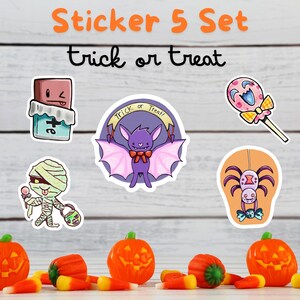May include: A set of five Halloween-themed stickers featuring a bat, a mummy, a spider, a candy, and a chocolate bar. The stickers are on a white wooden background with orange and yellow candy corn scattered in the foreground. The stickers are all in a cartoon style and have a cute and whimsical feel.